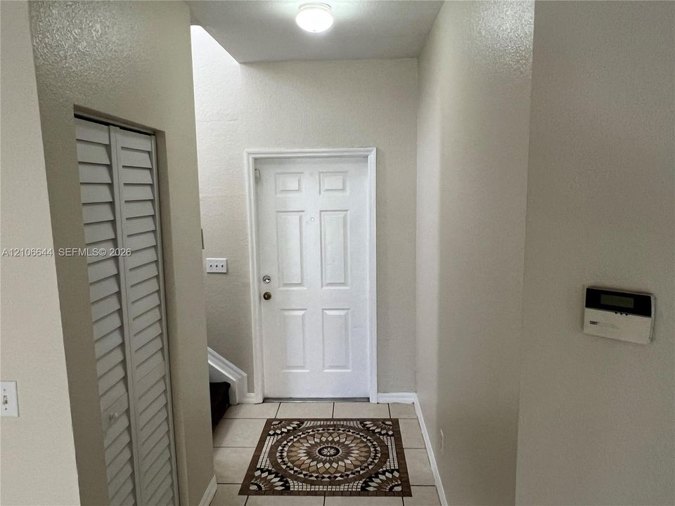 Entryway featuring a multi-panel door, tile flooring, flush-mount ceiling lighting, and a bi-fold louvered closet door