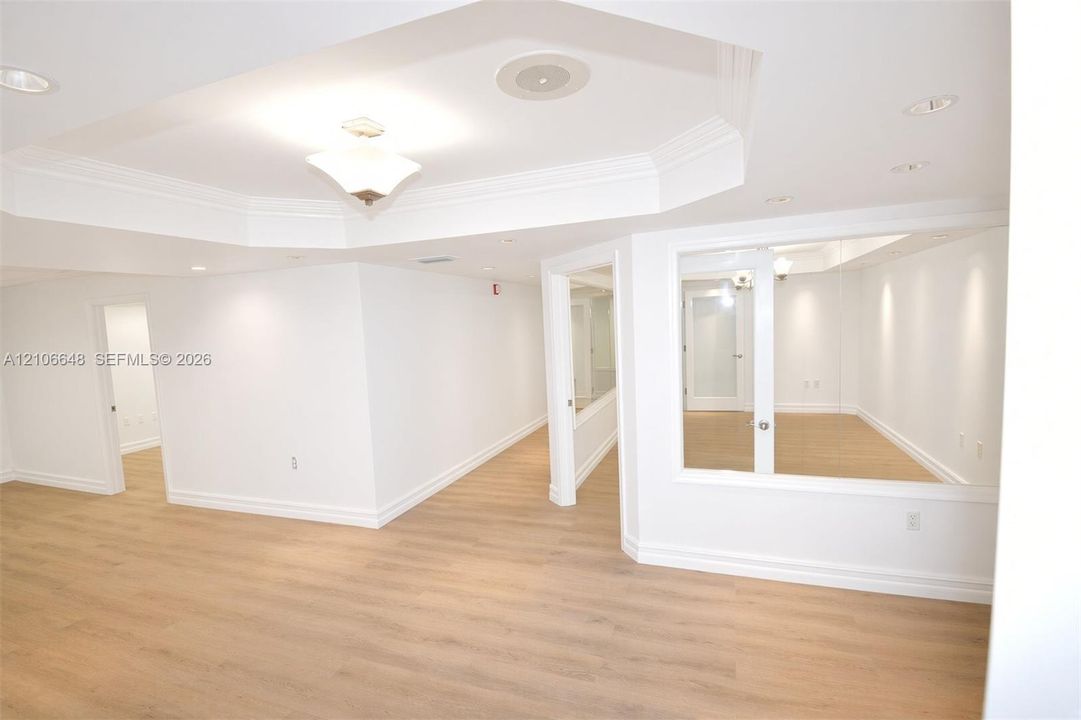 Tray ceiling featuring recessed lighting, wood-finish flooring, and glass partition wall panels
