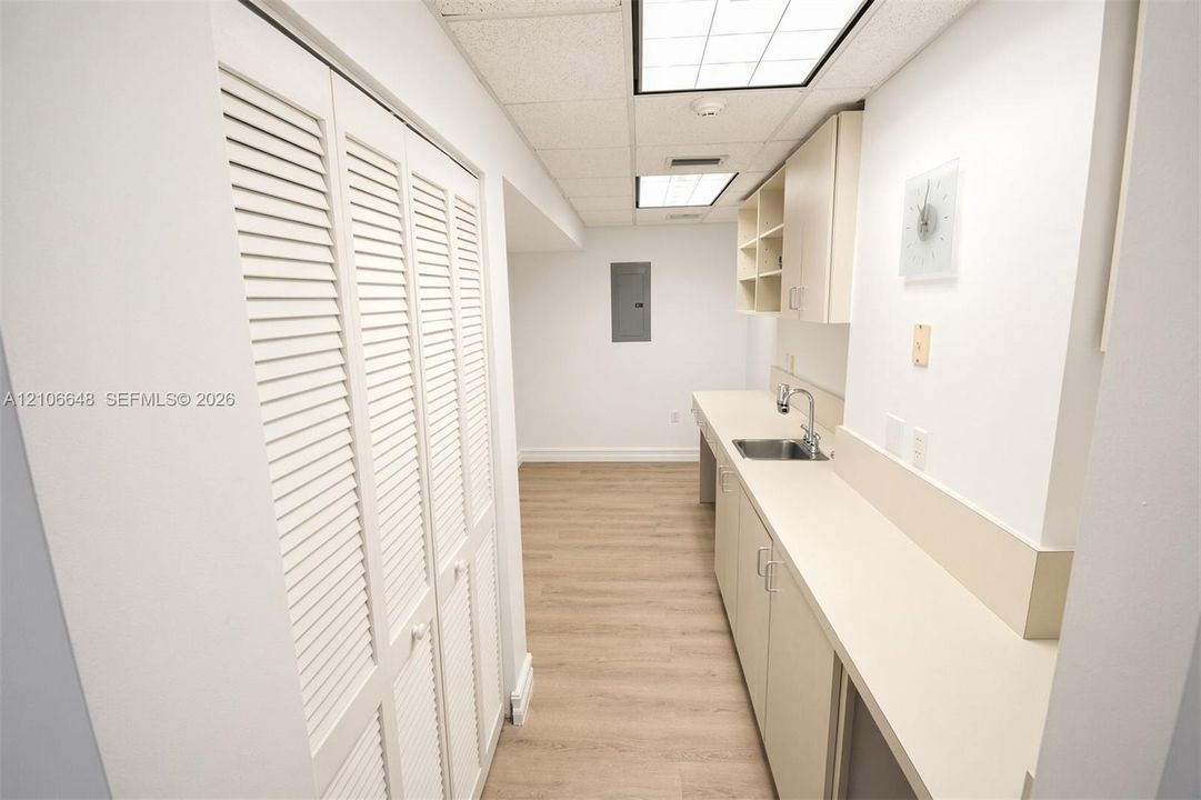 Built-in cabinetry with integrated sink, expansive solid-surface countertop, wood-finish flooring, and louvered bi-fold closet doors