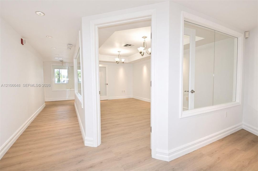 Interior space featuring wood-finish flooring, recessed lighting, multi-arm chandeliers, and interior glass partition walls