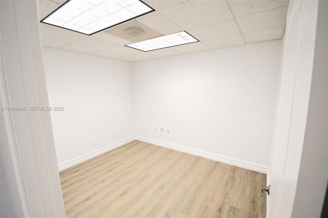 Interior room featuring neutral wall finishes, light wood-finish flooring, and recessed drop-ceiling light fixtures