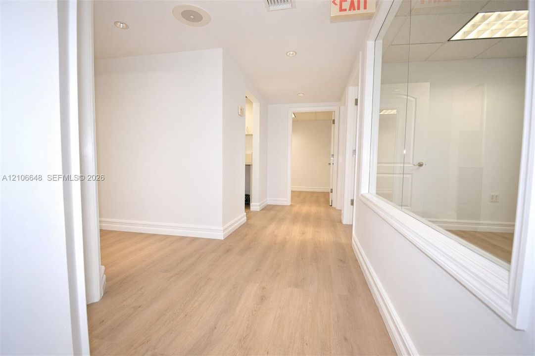 Interior corridor featuring wood-finish flooring, recessed ceiling lighting, and a large glass-paneled partition