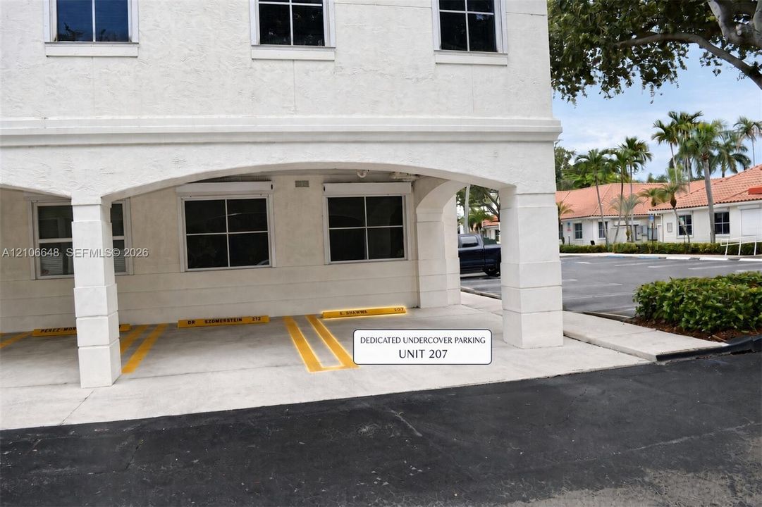 Covered parking area featuring structural pillars, stucco exterior finish, and multi-pane windows