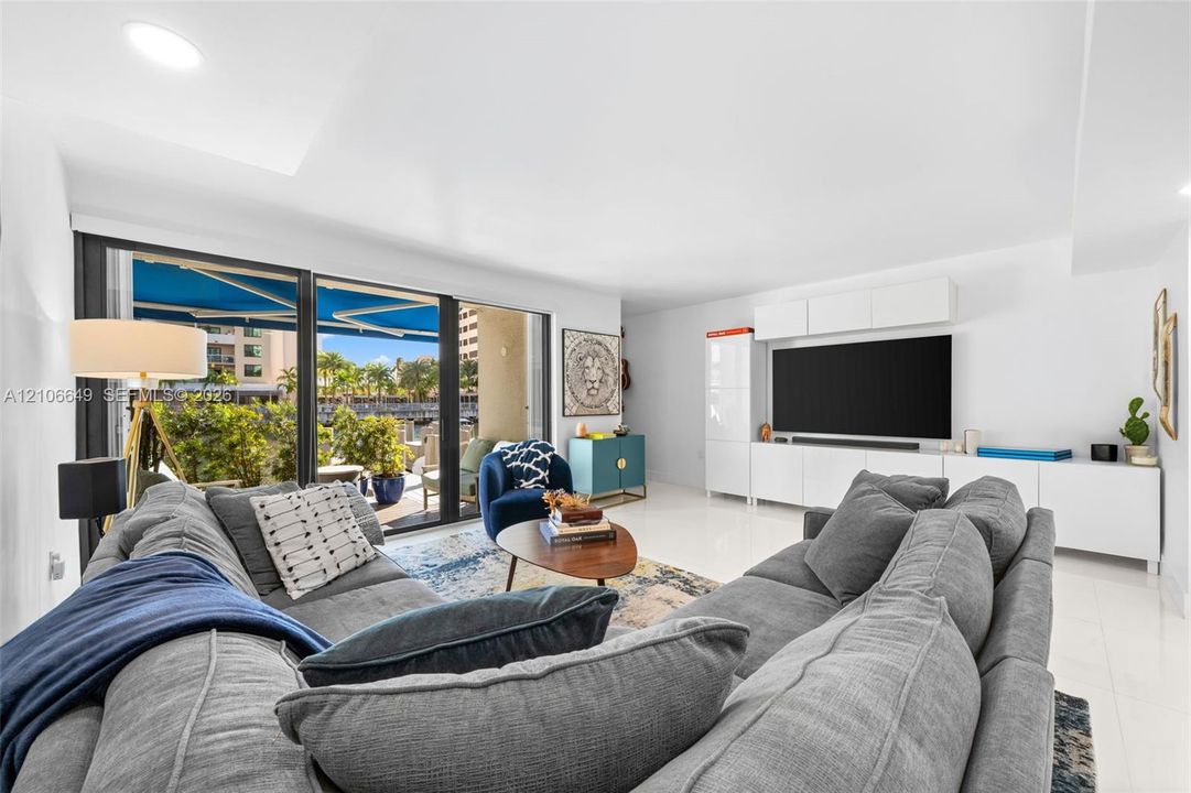 Hallway featuring polished tile flooring, recessed lighting, and a bathroom equipped with a floating vanity, light-toned wood-finish cabinetry, and a stone-tiled accent wall