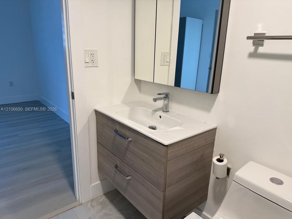 Floating vanity featuring a wood-finish cabinet, white integrated sink, polished chrome faucet, and rectangular medicine cabinet