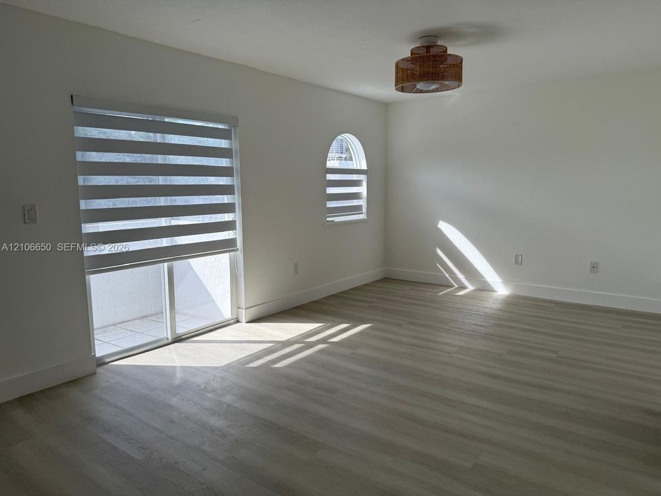 Wood-finish flooring, sliding glass door, arched window, and textured drum ceiling fixture