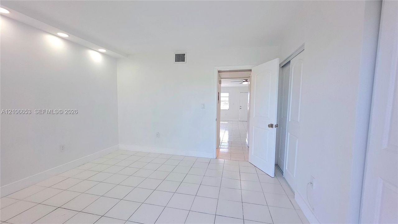 Neutral-toned interior featuring large-format ceramic tile flooring, recessed cove lighting, and a sliding-door closet with paneled detailing