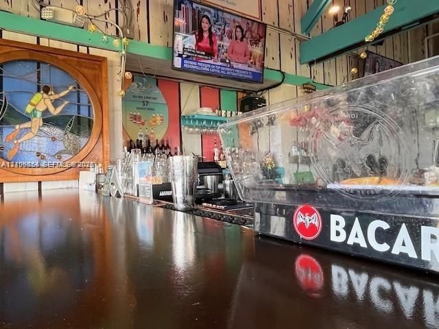 Bar featuring a polished dark-tone countertop, decorative circular stained-glass wall art, vertical wood paneling, and integrated stemware storage