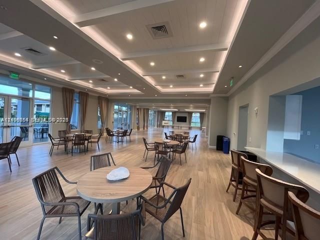 Expansive common area featuring wood-finish flooring, coffered ceilings with recessed lighting, and a built-in service counter