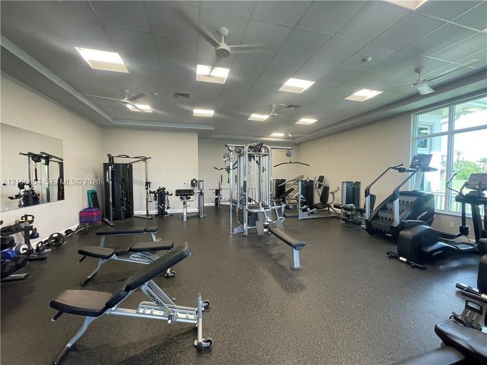 Fitness center with durable rubber flooring, recessed lighting, and multiple ceiling fans
