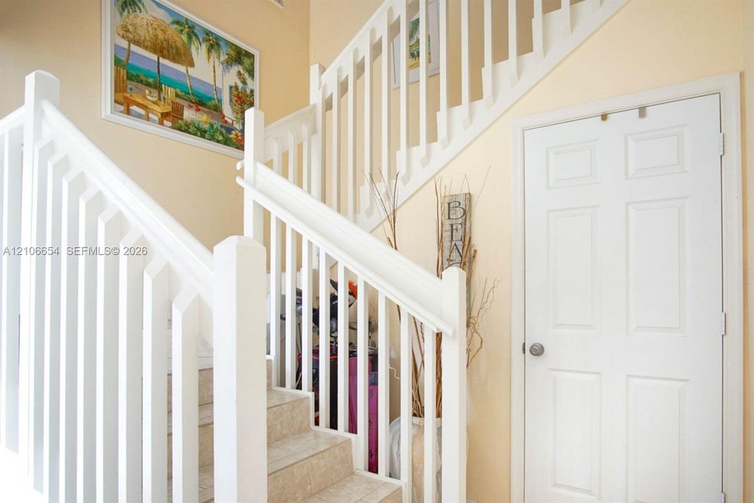 Staircase featuring white balustrades, stone-finish steps, and a white paneled door