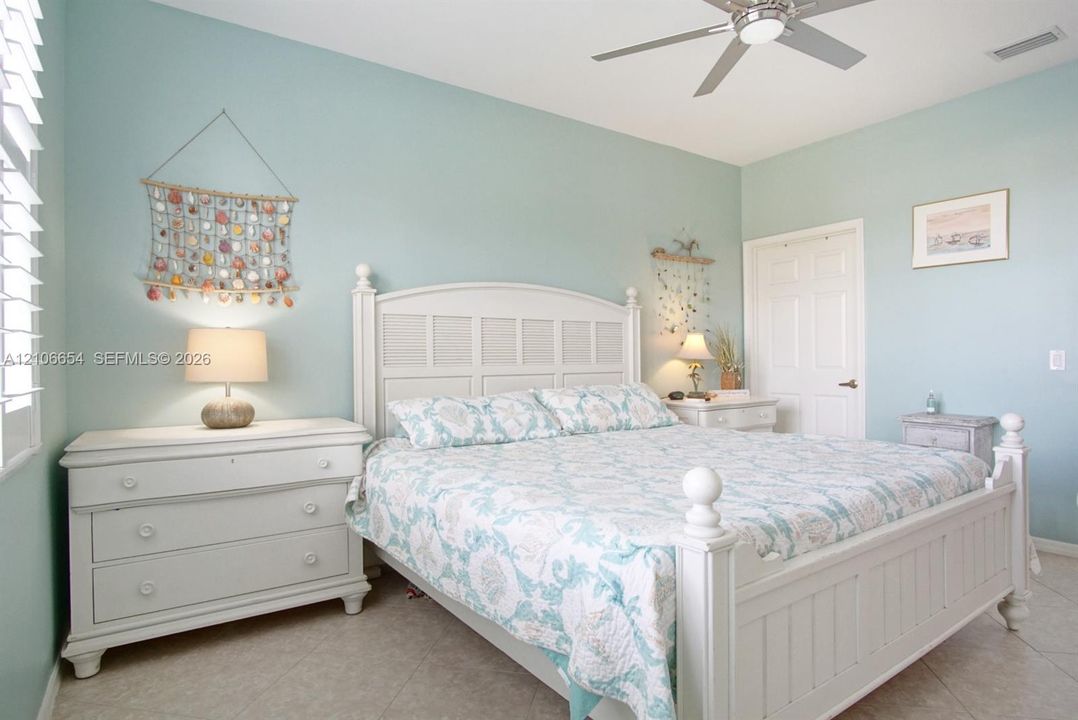 Room featuring tile flooring, six-panel interior door, and ceiling fan with integrated lighting