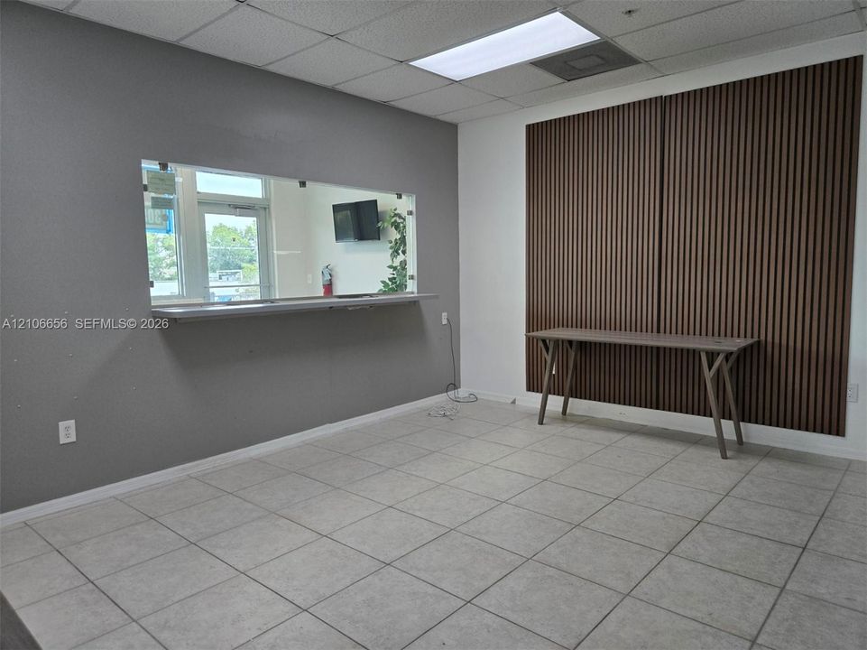 Interior space featuring a slatted wood-finish accent wall, tile flooring, and an integrated service window with a stainless steel counter