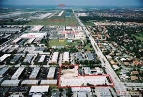 Aerial perspective of a rectangular parcel featuring an L-shaped building, paved surface area, and perimeter landscaping