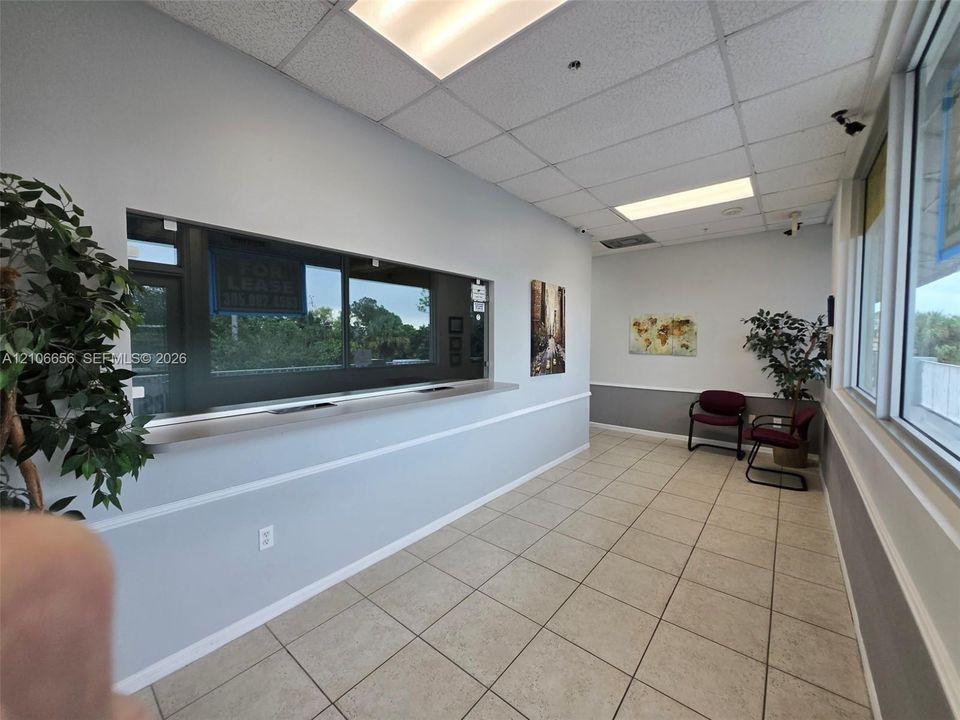 Reception area featuring large windows, ceramic tile flooring, a service counter, and recessed drop-ceiling lighting
