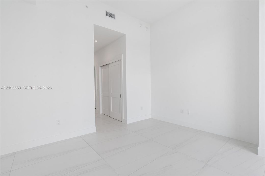 Interior space featuring large-format rectified tile flooring, recessed ceiling lighting, and double-panel sliding closet doors