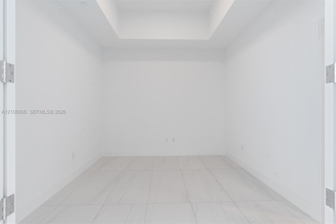 Interior space featuring a recessed ceiling, white walls, and large-format tile flooring