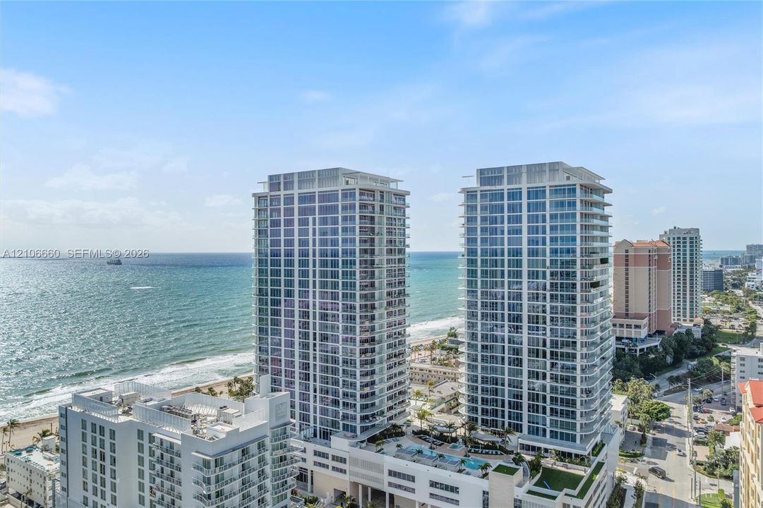 High-rise residential towers featuring glass-curtain wall facades, exterior balcony systems, and a multi-level podium deck with a pool