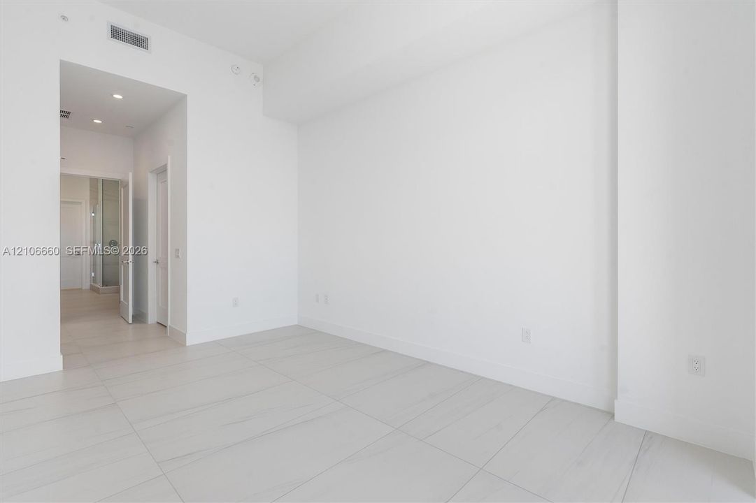 High-ceiling interior featuring smooth white walls, large-format tile flooring with marble-style veining, recessed lighting, and solid-core interior doors