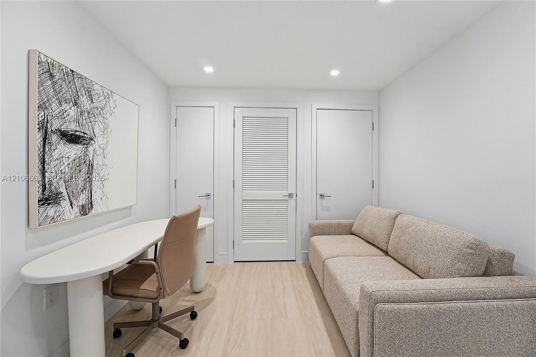 Interior space featuring recessed lighting, wood-finish flooring, two solid-core interior doors, and a central louvered-panel door with brushed nickel hardware