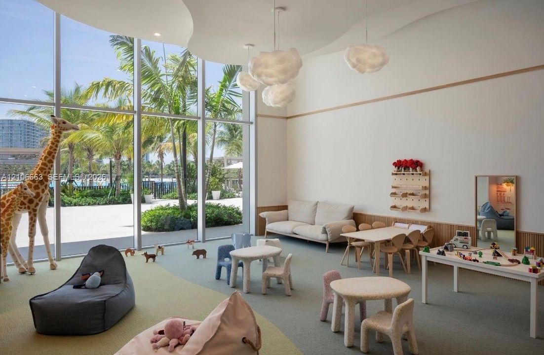 Floor-to-ceiling windows, high ceilings with sculptural pendant lighting, wood-paneled wall accents, and wall-to-wall carpeting