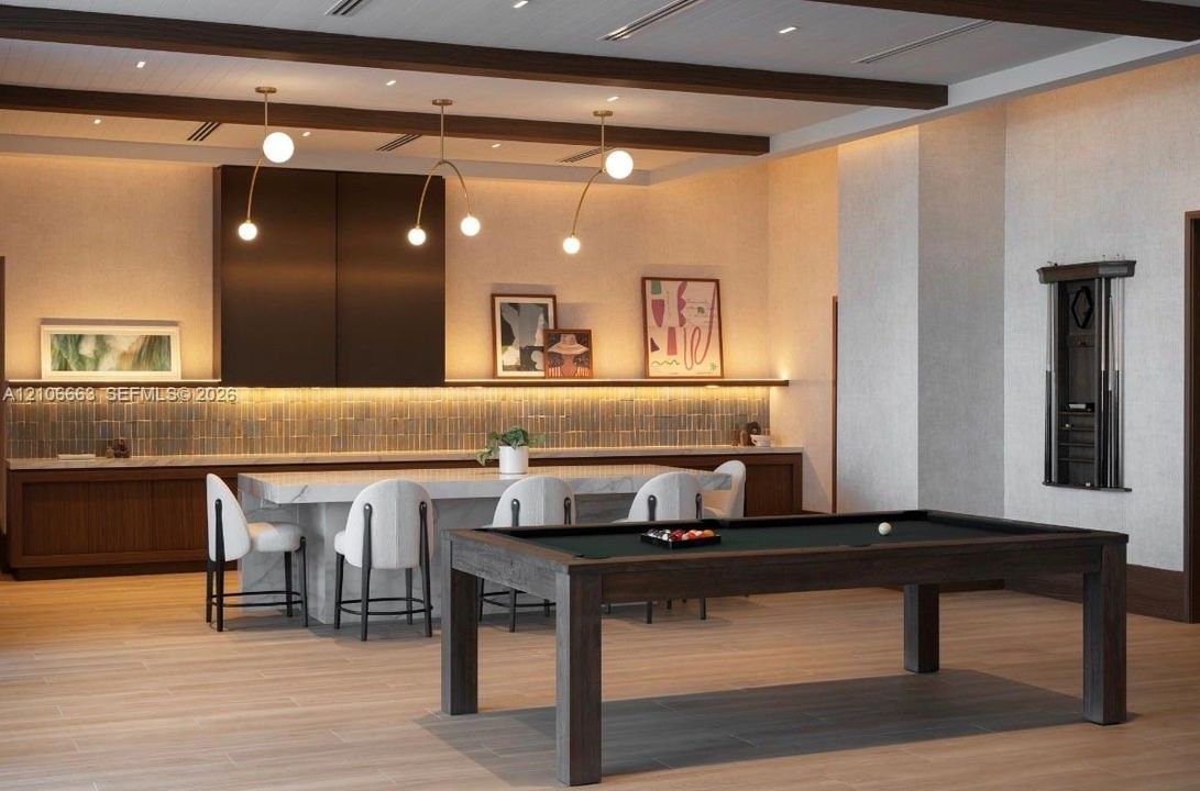 Custom cabinetry with integrated under-cabinet lighting, stone-surface kitchen island, wood-finish flooring, and decorative ceiling beams