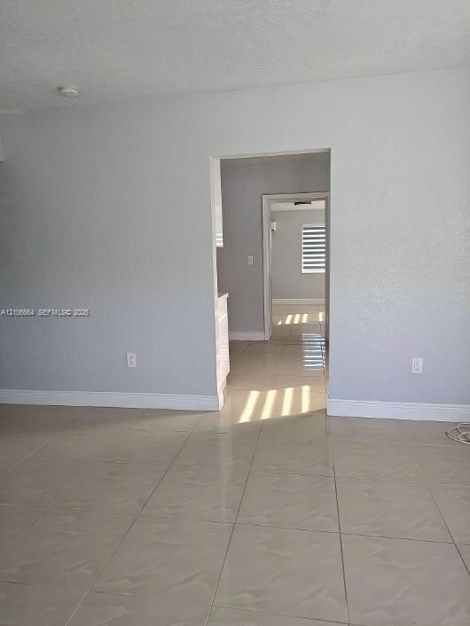 Neutral-toned ceramic tile flooring, textured wall surfaces, and horizontal window blinds
