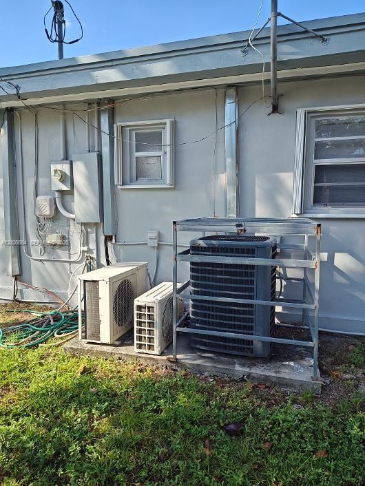 Exterior HVAC system featuring a condenser unit with a metal protective cage and two secondary climate control units mounted on a concrete pad