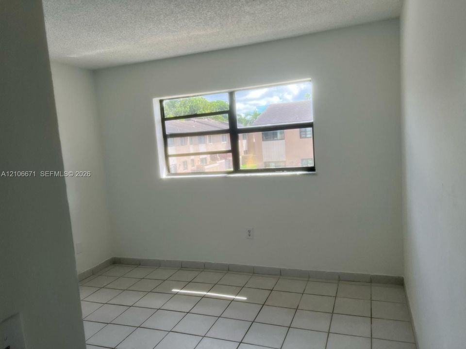 Interior room featuring ceramic tile flooring, neutral wall finishes, and a multi-pane window with dark frames
