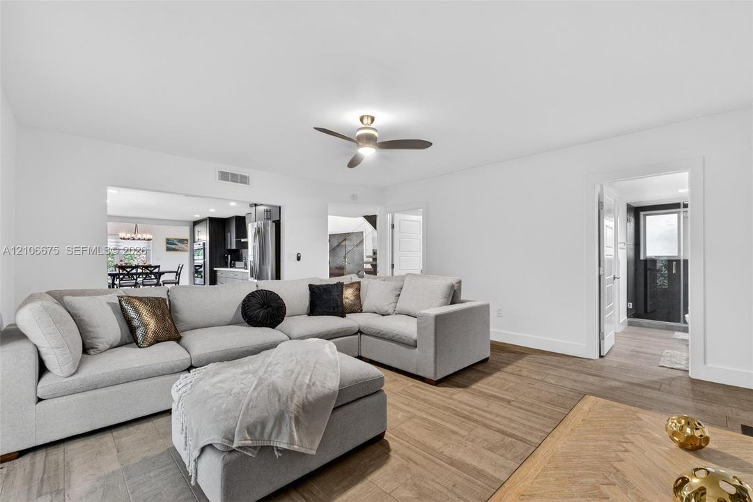 Living area featuring wood-finish flooring, a ceiling fan with integrated lighting, and white walls