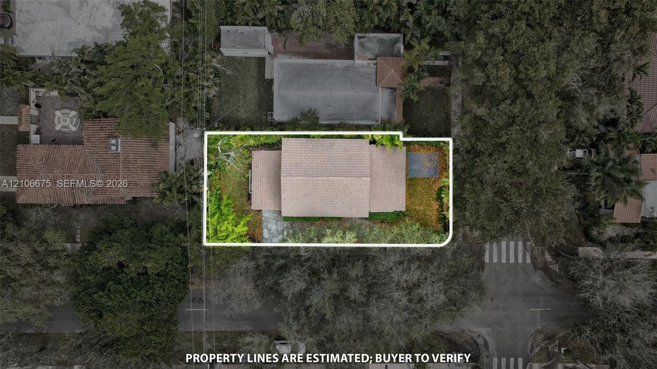 Aerial view of the property lot featuring mature trees, landscaped grounds, a shingled roofline, and hardscaped walkways