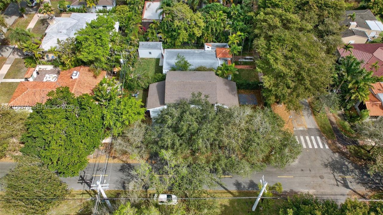 Aerial perspective of property featuring mature trees, corner lot positioning, and expansive grounds