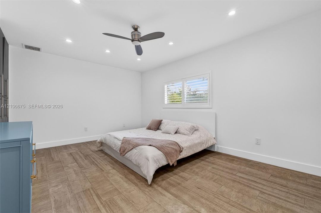 Wood-finish flooring, recessed lighting, ceiling fan, and window featuring plantation shutters