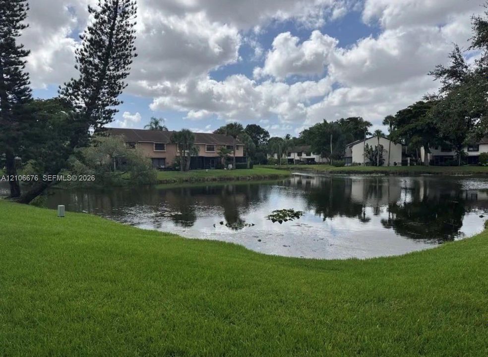 Waterfront property featuring a manicured lawn, mature trees, and landscaping