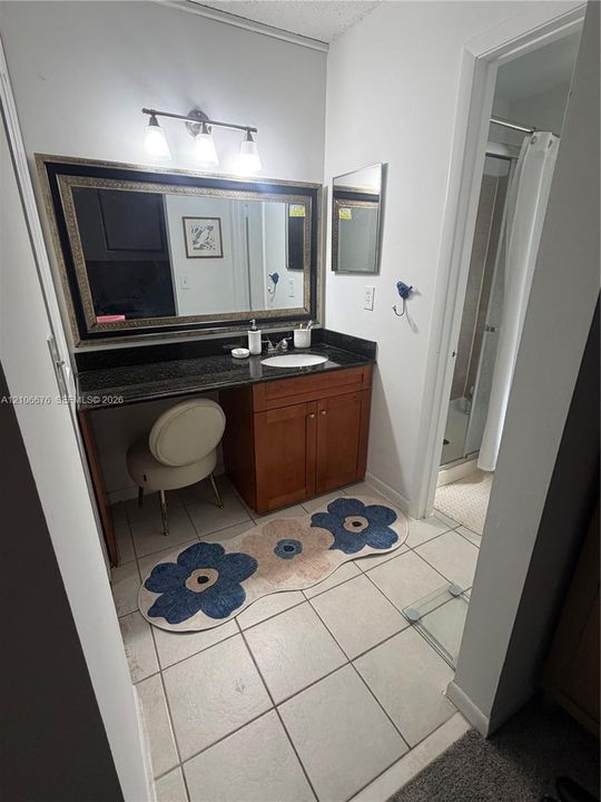 Bathroom vanity featuring a stone countertop, an integrated oval basin, warm-toned wood cabinetry, and a three-light wall-mounted fixture