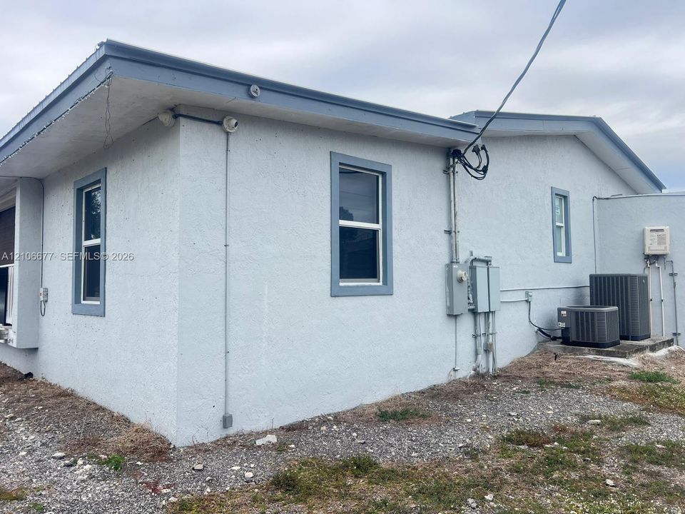 Stucco exterior featuring multi-paned windows, neutral trim, and dual exterior HVAC condenser units