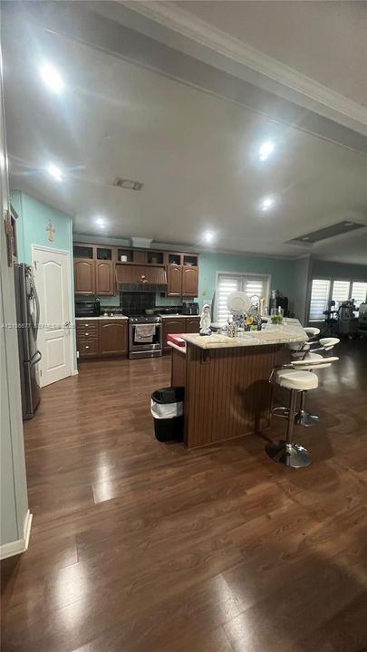 Kitchen featuring wood cabinetry, a center island with a stone-finish countertop, recessed lighting, and wood-finish flooring