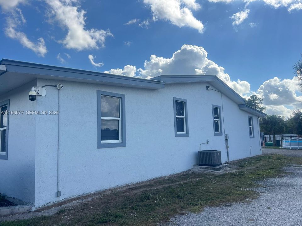 Stucco exterior featuring dual-pane windows, a mounted security camera, and an external HVAC unit