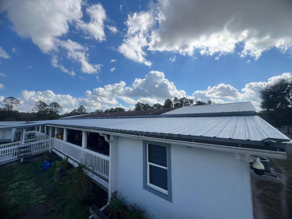 Exterior featuring a white metal roof, a full-length covered porch with a white railing, and exterior white siding