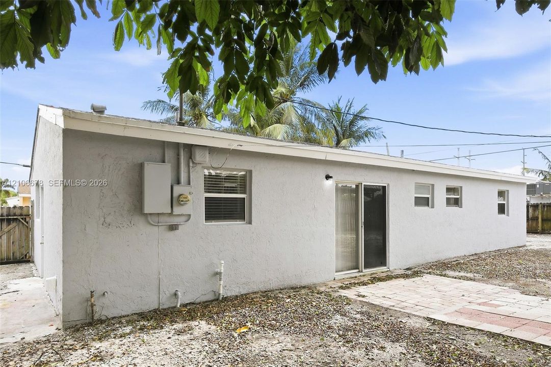 Stucco exterior, sliding glass door, paved patio, and multiple horizontal slider windows