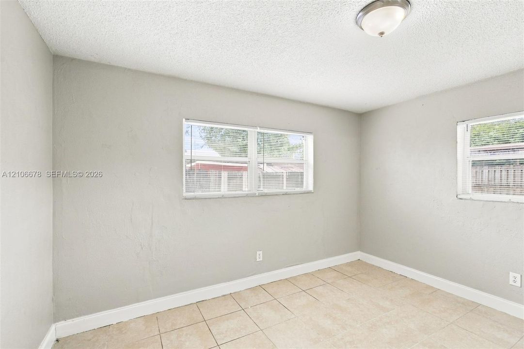 Neutral-toned walls, large windows with integrated blinds, and ceramic tile flooring