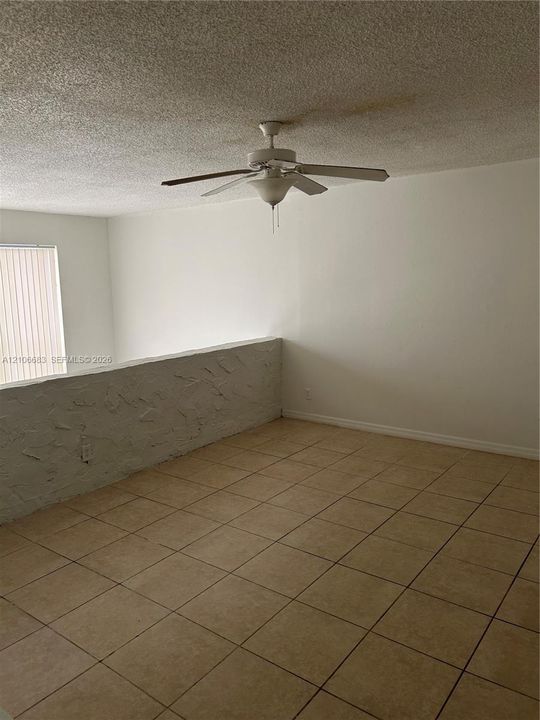 Ceramic tile flooring, textured wall accent, and ceiling fan with integrated light fixture