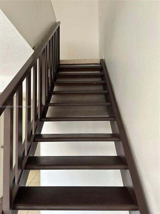 Open-riser staircase featuring stained wood treads and a matching dark wood railing