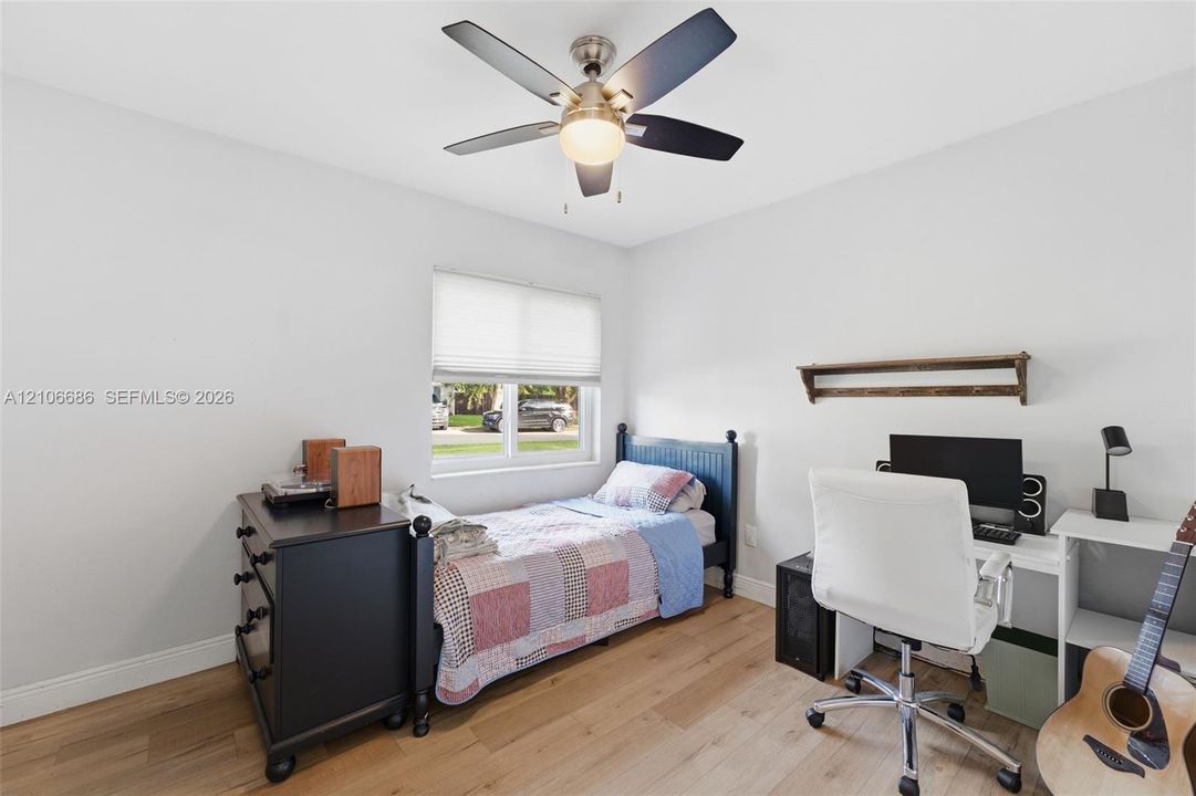 Wood-finish flooring, central ceiling fan with integrated lighting, window with built-in shade, and wall-mounted shelving