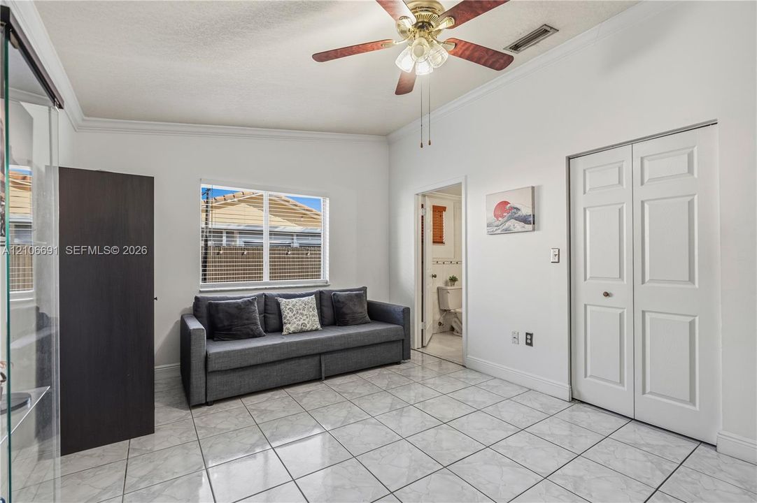 Interior space featuring polished tile flooring, a multi-blade ceiling fan with integrated lighting, and a double-door closet with paneled detailing