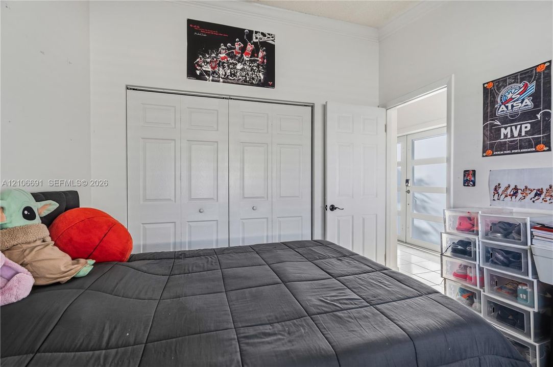 Interior room featuring neutral wall paint, white crown molding, dual-panel closet doors, and tile flooring