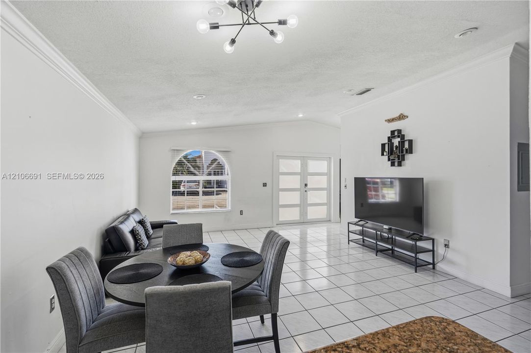 Ceramic tile flooring, multi-pane arched window, dual-entry doors with glass inserts, and modern multi-arm ceiling light fixture
