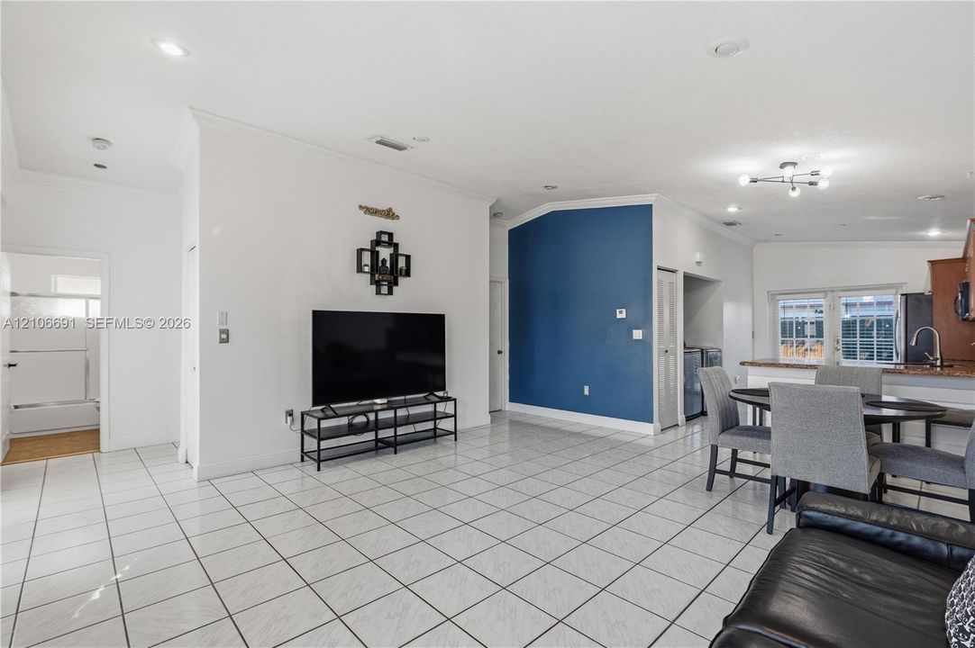 Open-concept interior featuring large-format ceramic tile flooring, vaulted ceilings, recessed lighting, and a distinct blue accent wall