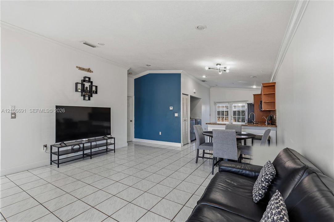 Open-concept interior featuring light-colored tile flooring, recessed lighting, and a prominent blue accent wall