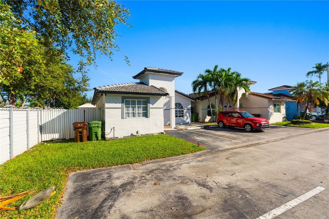 Stucco exterior featuring a tiled hip roof, arched window details, and paved surface parking